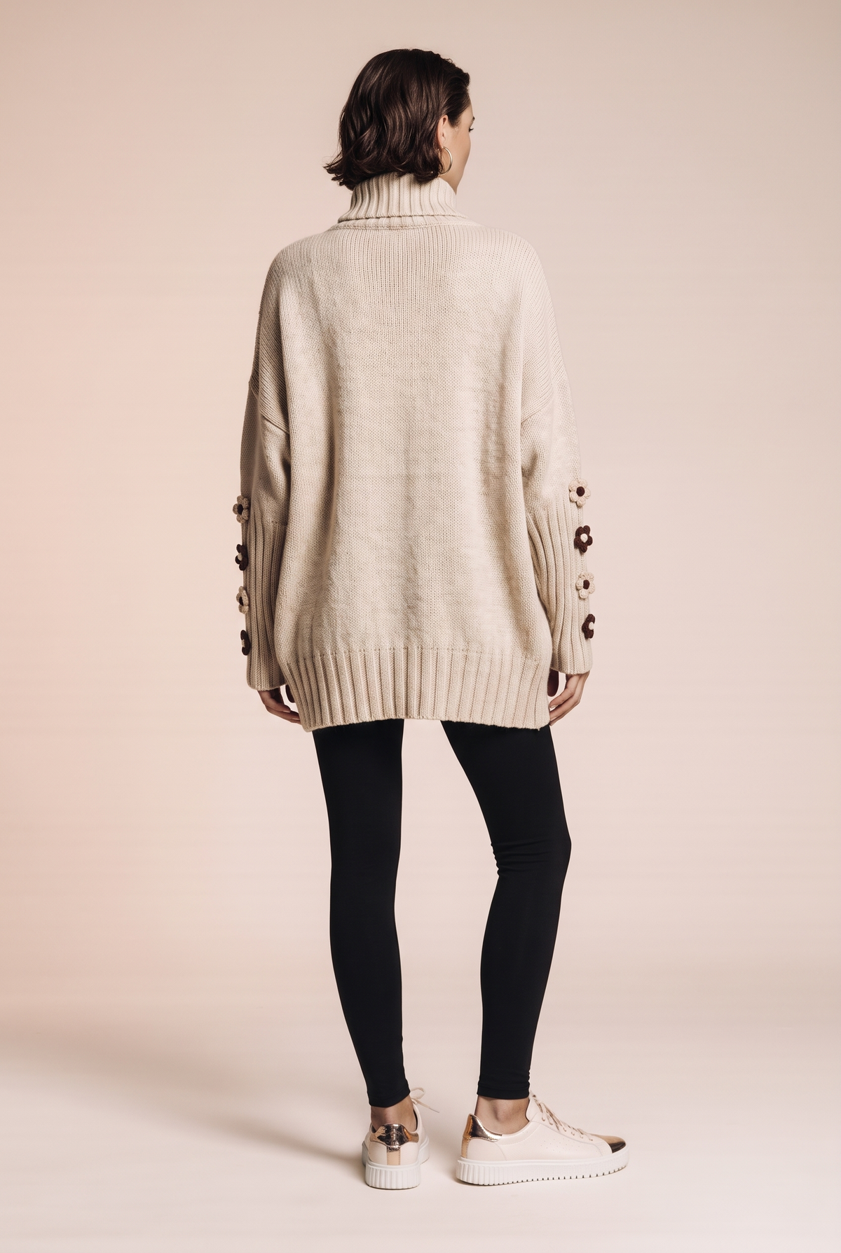 Dzianinowy sweter oversize z kwiatowymi naszyciami na rękawach